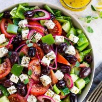 greek salad lettuce_ tomatoes_ cucumbers_ green and red bell peppers_ olives_ feta cheese_ lemon juice_ olive oil